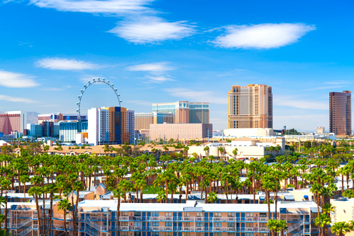 Uitzicht op Las Vegas met de Strip vol hoge hotels en neonverlichting, drukke wegen en een skyline in de woestijn onder een heldere lucht.